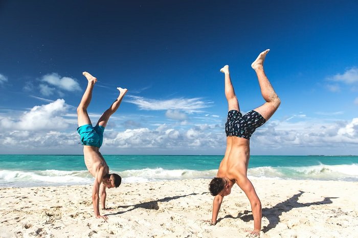 Two men doing handstands on a beach for a best friend photoshoot