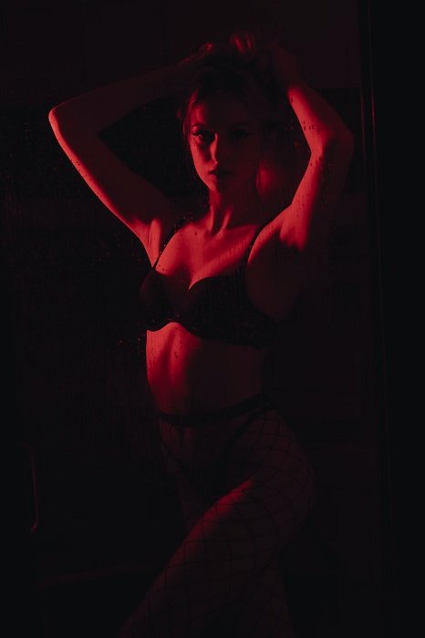 Woman in lingerie in red light posing for boudoir photography