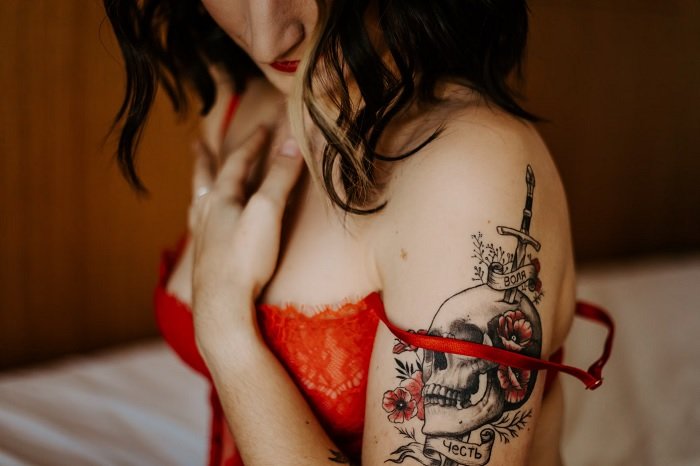 boudoir pose of a woman depicting her torso with red bra and skull tattoo