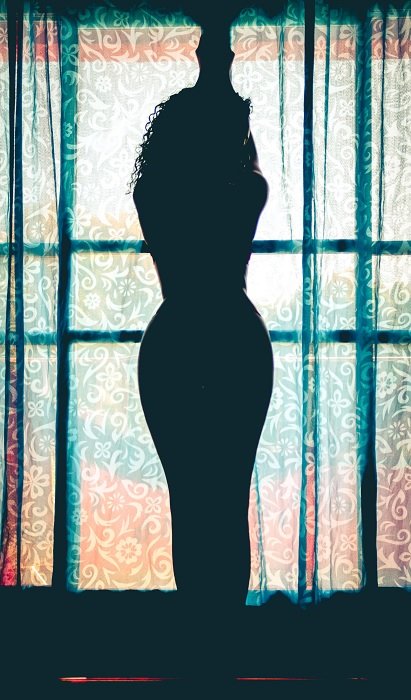 Woman standing in front of a window as an example of boudoir poses