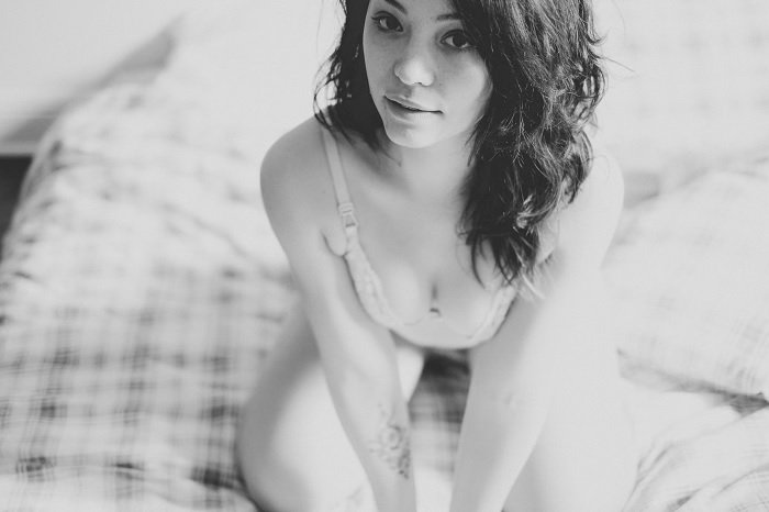 Black and white photo of woman kneeling on bed for a boudoir photoshoot