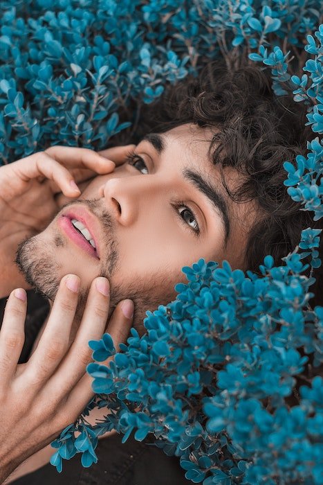 Man holding his face surrounded by flowers
