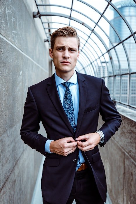 Man posing in a suit buttoning his suit jacket