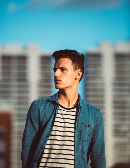 man with good jawline posing against a city skyline