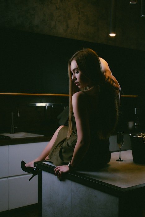 Model pose idea with a woman sittting on a kitchen looking down and over her shoulder