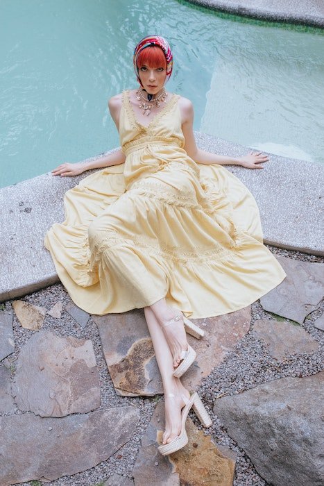 Woman laying by pool in a yellow dress and head scarf as an example of model poses