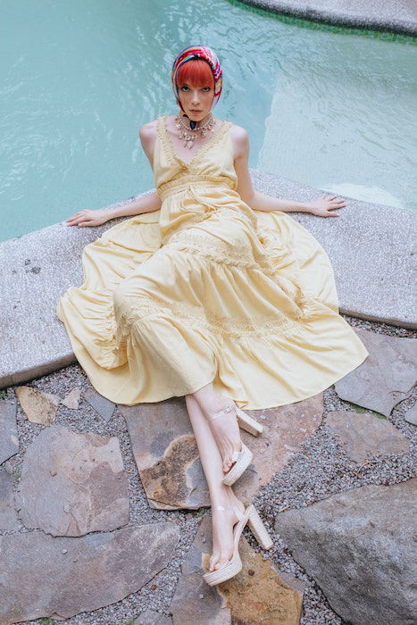 Woman laying by pool in a yellow dress and head scarf as an example of model poses