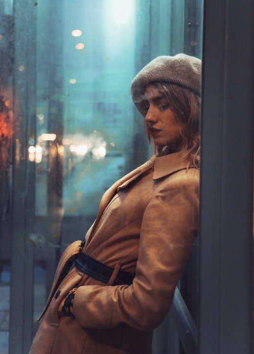 Moody photo of a woman leaning inside a phonebooth as an example of model poses