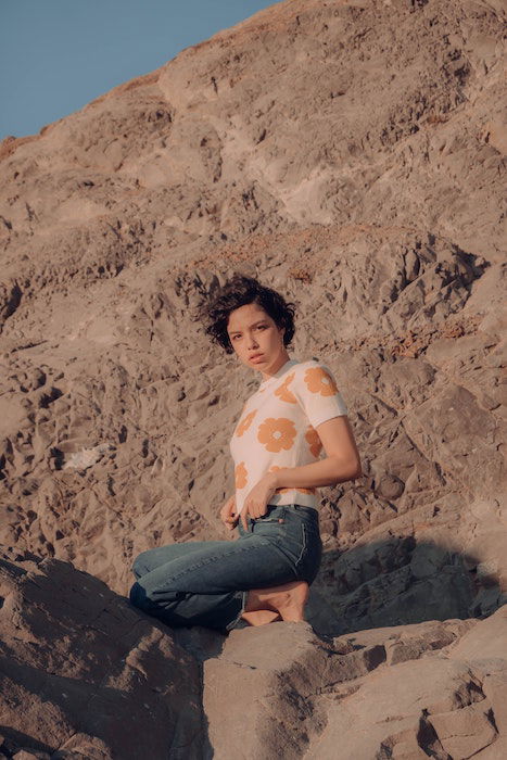 Woman kneeing on rocks outdoors as an idea for model poses