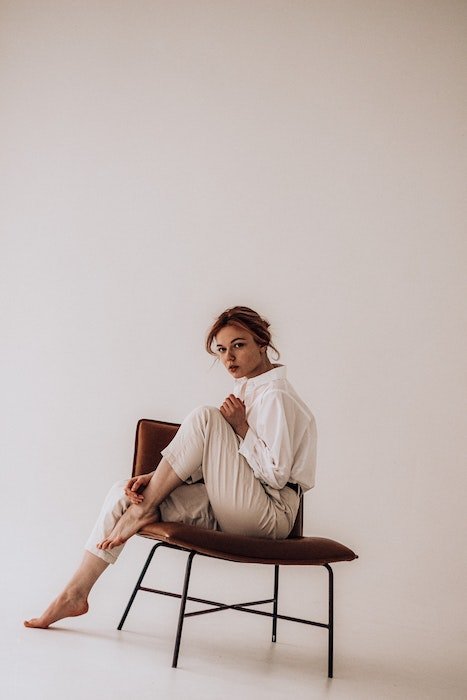 Woman sitting in chair with one leg up as an idea for model poses