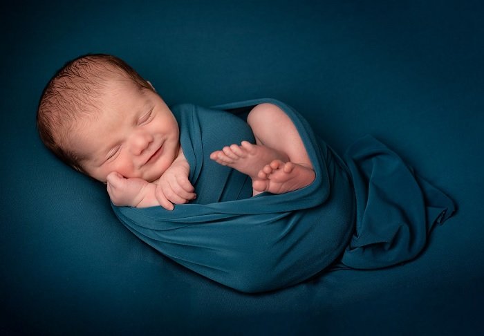 Baby wrapped in blue blanket for a newborn photoshoot