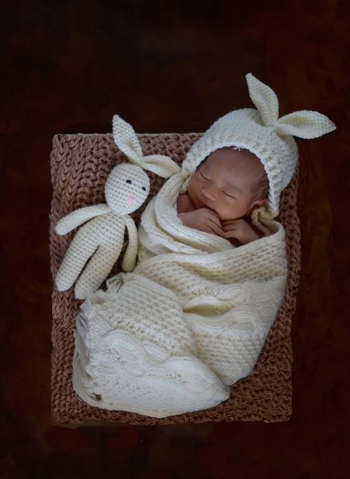 Newborn photo idea of a baby in knitwear with matching toy
