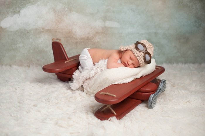 Baby sleeping in aviation theme scene as an example of newborn photo ideas