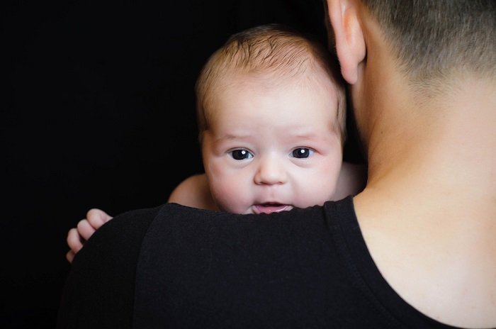 Baby looking over father's shoulder as an idea for newborn photos