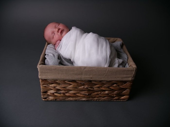Baby wrapped in a blanket in a basket as newborn photo idea