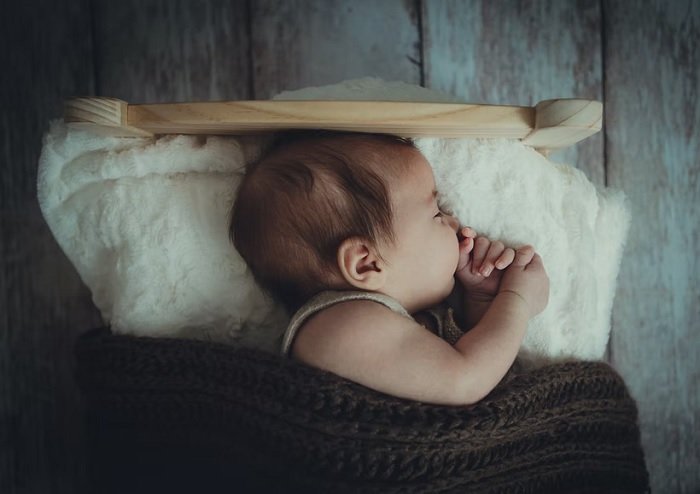 Baby sleeping in a miniature bed for a newborn photoshoot