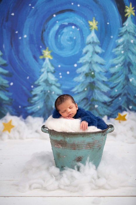 Newborn in a bucket in a snow scene as an example of newborn photo ideas
