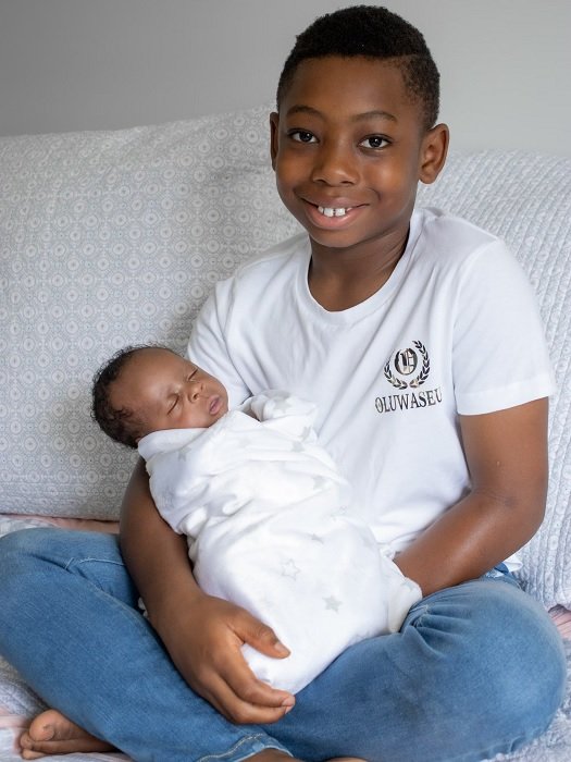 Newborn photo idea of a young boy holding a newborn baby