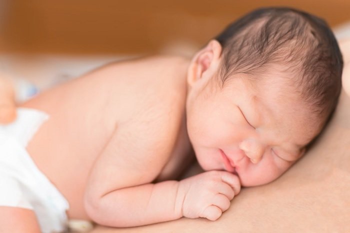 Newborn baby sleeping on stomach of parent