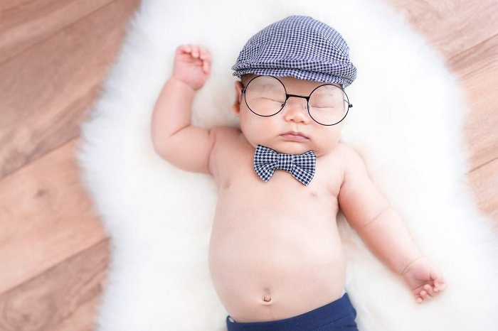 Baby boy in glasses, hat and bowtie as a funny newborn photoshoot idea