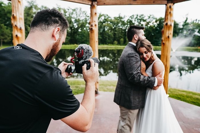 Photographer taking pictures of a wedding couple near a small lake