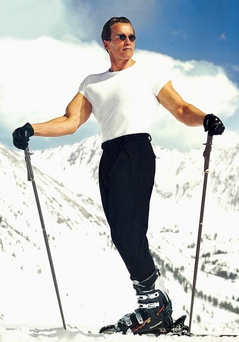 阿诺德·施瓦辛格在雪山背景的滑雪板上滑雪
