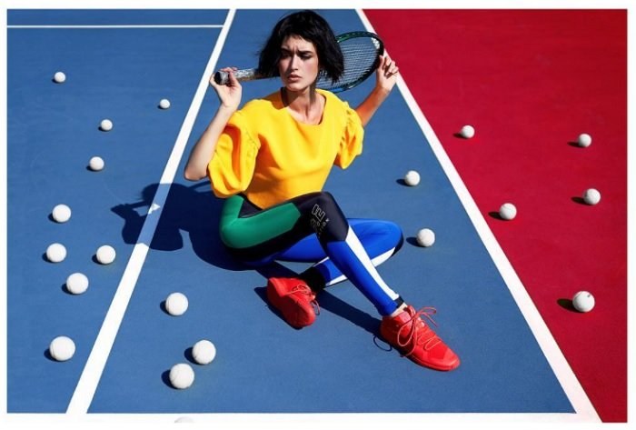 一个穿着五颜六色衣服的女人坐在网球场上