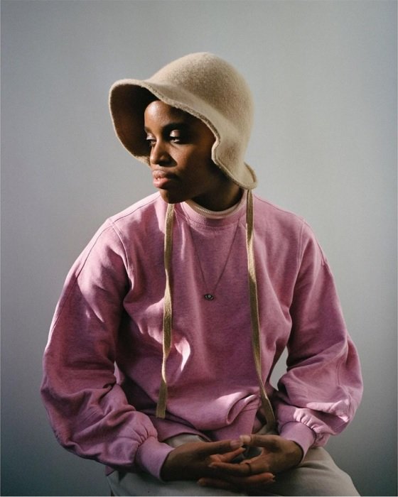 一个女孩的肖像，穿着粉红色的套头衫，戴着帽子