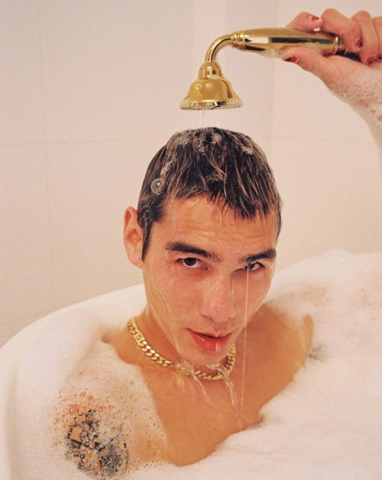 portrait of a man with a gold chain taking a bubble bath