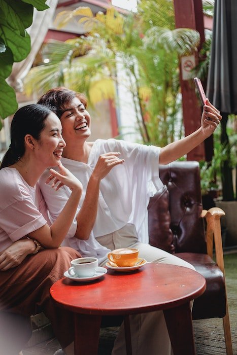 Two woman laughing while posing for a selfie