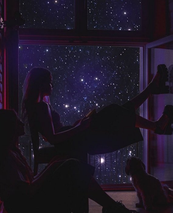 Two people and a cat sitting in front of a starry window