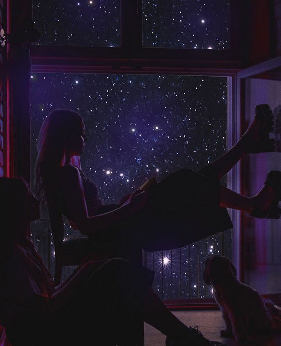 Two people and a cat sitting in front of a starry window for creative editing ideas