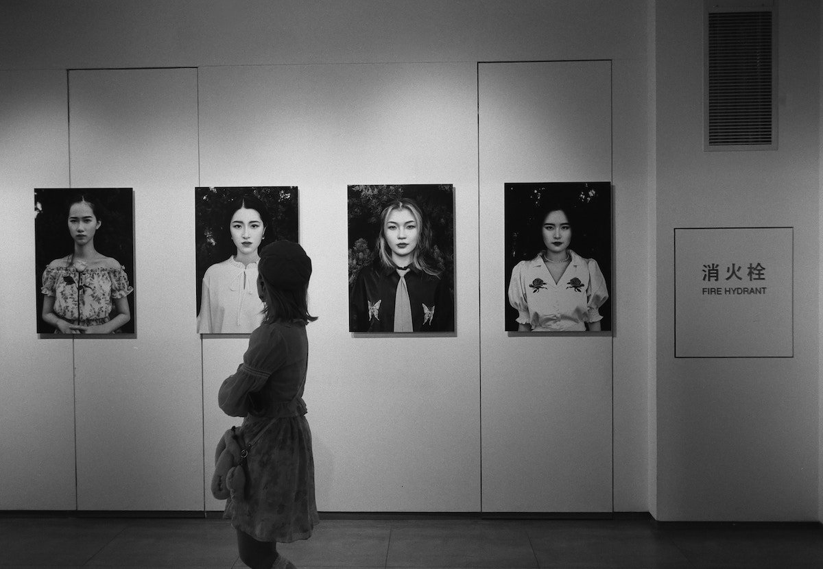A woman walking and looking at portrait photos in a gallery