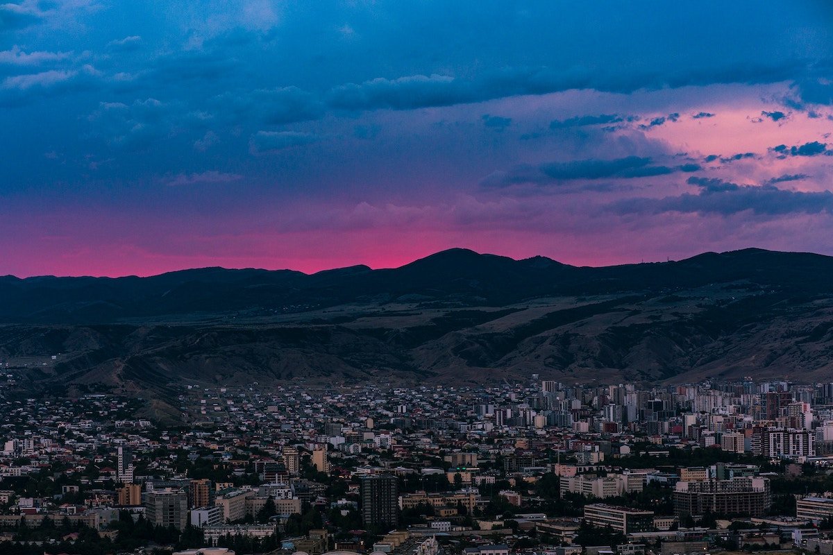 A city landscape with mountains and a blue and pinky sky