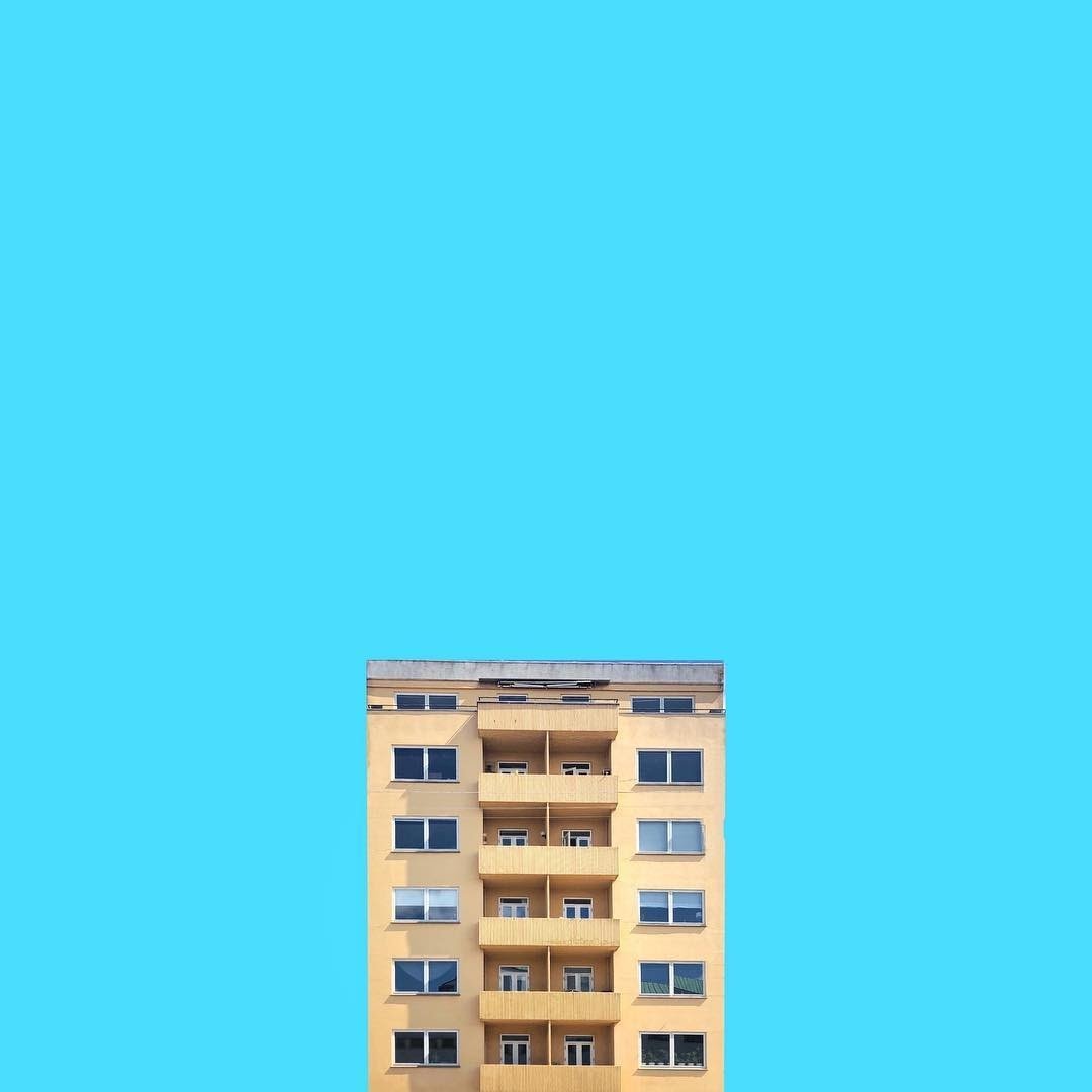 The top of an apartment building centered against a blue sky
