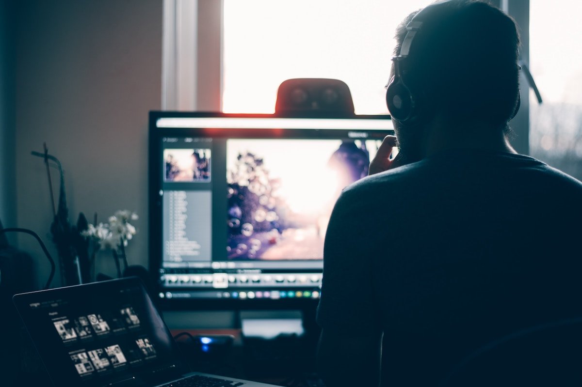 Silhouette of a man editing photos on a computer and laptop