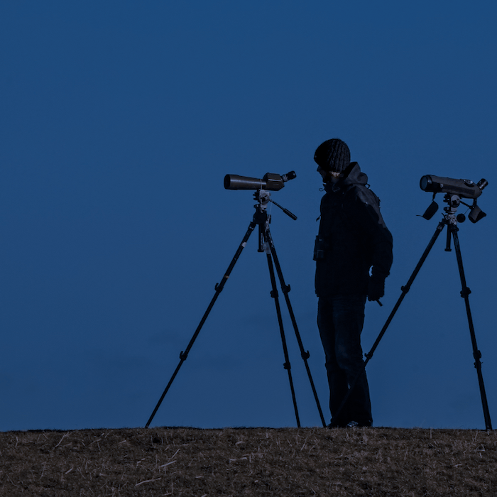 Person standing with two telescopes for astrophotography