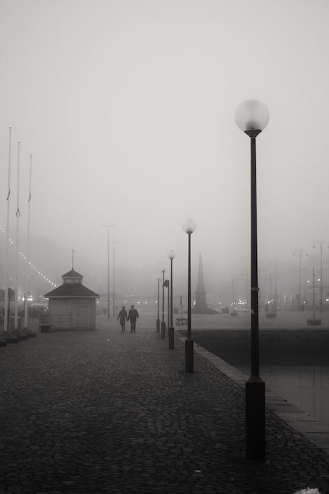 A foggy city square with lampposts