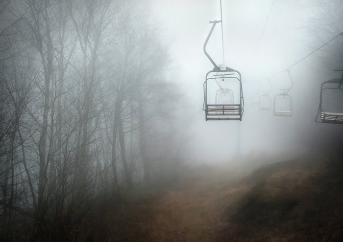 A cablecar is shown in a foggy forest