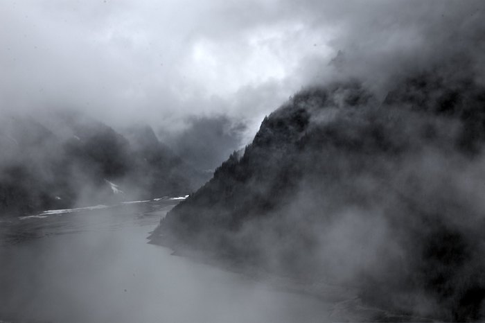 A foggy view of a mountain valley with a lake at the bottom