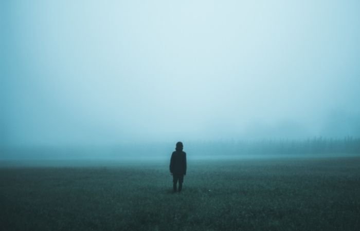 a blue tinted fog photoshoot of a man in a field