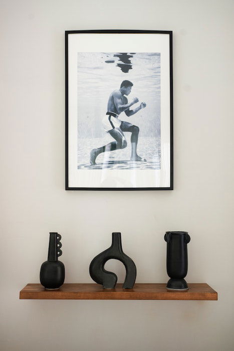 A framed photo of Mohammed Ali hangs above a wooden shelf