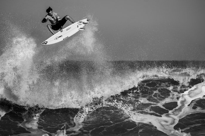 A black and white image of a surfer getting airtime