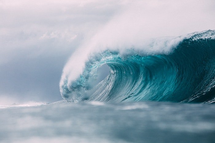 A wave breaks with deep blue colors