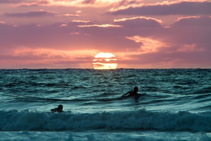 Surfers in the water at sunset as an idea for surf photography