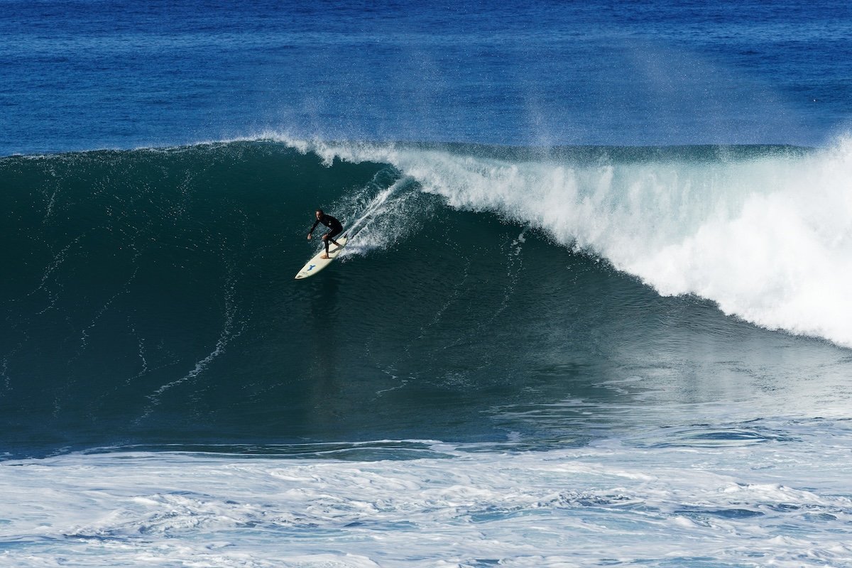 A rider at the top part of a barrel wave with the ocean in the background as an example of surf photography