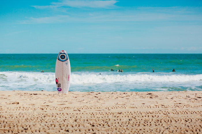 A surfboard standing in front of a blue ocean