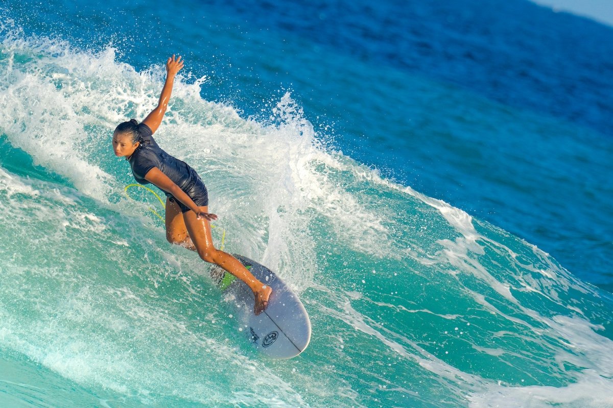 A surfer leaning forward on a surfboard riding a wave as an example of surf photography