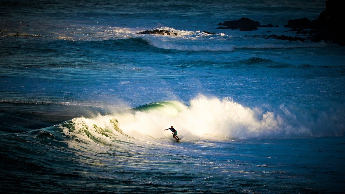 Seascape shot of a surfer riding a wave surrounded by the ocean as an example of surf photography