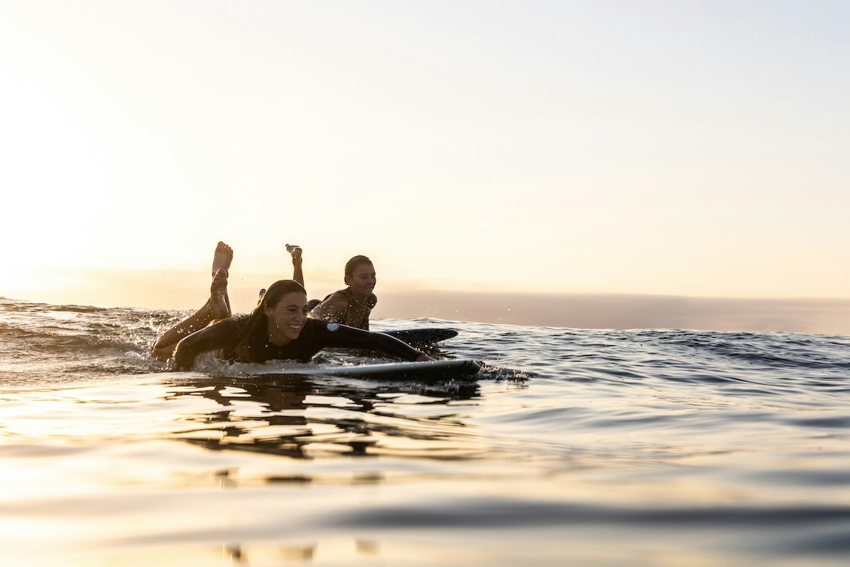 Two surfers paddling on their surfboards on the ocean as an example of surf photography
